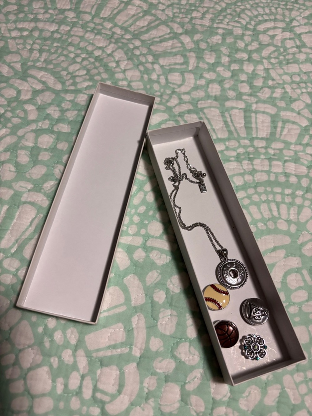 Silver necklace with assorted pop ins . Baseball,cheer,basketball and a gem .